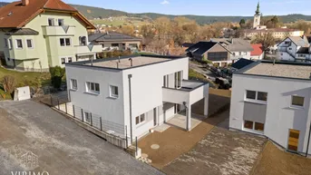 Moderne Neubau-Doppelhaushälfte mit Flachdach und Blick auf die umliegende Ortschaft.