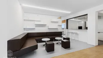 Moderner Loungebereich mit bequemen Ledersofas, weißen Tischen und einer integrierten Küchenzeile.