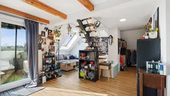 Helles Wohnzimmer im Dachgeschoss mit Holzbalken, Laminatboden und Zugang zu einem Balkon.