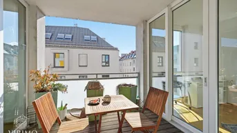 Balkon mit Holzboden und Sitzgelegenheiten, bietet einen weiten Blick über die Dächer der Stadt.