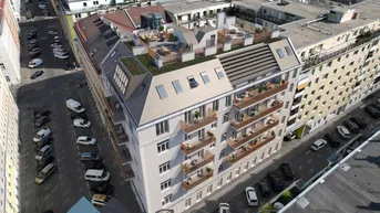 Luftaufnahme eines modernen Wohngebäudes mit Dachterrassen und Balkonen in städtischer Umgebung.