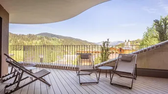Geräumiger Balkon mit Holzfußboden und Liegestühlen, bietet einen weiten Blick auf die umliegende Berglandschaft.
