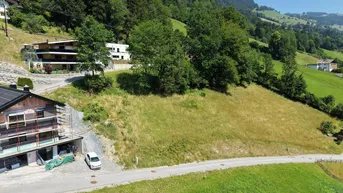 Luftaufnahme eines Baugrundstücks mit einem im Bau befindlichen Gebäude und umliegender grüner Landschaft.