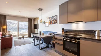 Offener Wohn-Essbereich mit integrierter Küche, Esstisch und Zugang zum Balkon.