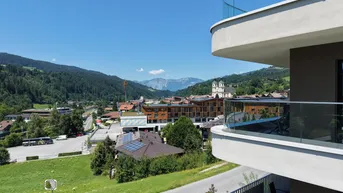 Geräumiger Balkon mit Glasbrüstung und weitem Blick auf die umliegende Berglandschaft und Stadt.