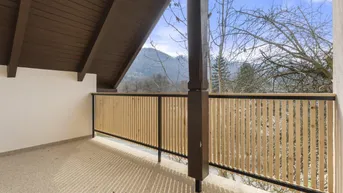 Geräumiger Balkon mit Holzelementen und weitem Blick auf die umliegende Berglandschaft.