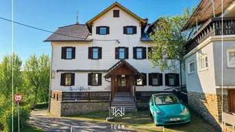 Traditionelles Haus mit weißer Fassade, Holzfensterläden und einem gepflegten Vorgarten.
