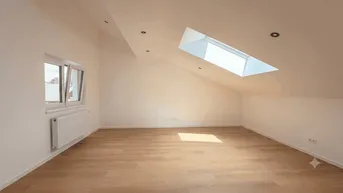 Heller Dachgeschossraum mit Dachfenster und Laminatboden, ideal für individuelle Gestaltung.