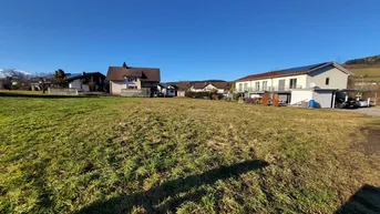 Weitläufiges Grundstück mit grüner Wiese und umliegenden Wohnhäusern unter blauem Himmel.