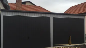 Moderne Doppelgarage mit schwarzen Toren und grauem Aufbau, gut gepflegt.