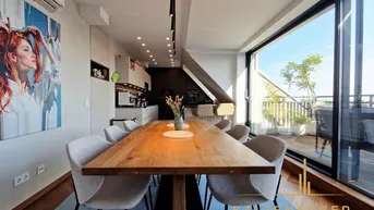 Heller offener Wohn-Essbereich mit Holztisch, modernen Stühlen und Zugang zur Dachterrasse.