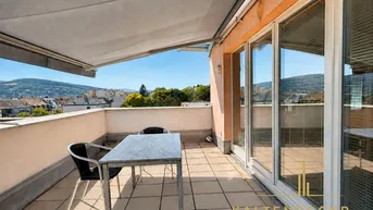 Geräumige Dachterrasse mit Markise, Esstisch und weitem Blick über die Stadt und Hügel.