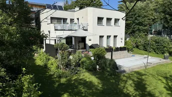 Modernes Wohnhaus mit großem Garten, Terrasse und üppiger Vegetation unter blauem Himmel.