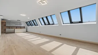 Heller, offener Wohnbereich mit Dachschrägenfenstern und integrierter Küche, ideal für modernes Wohnen.