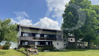 Großzügiger Gartenbereich vor dem Haus mit Rasenfläche, Bäumen und einem Grillplatz.