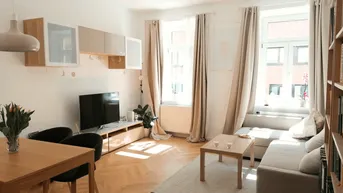 Heller Wohn- und Essbereich mit Fischgrätparkett, großen Fenstern und moderner Einrichtung.