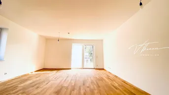 Heller, leerer Wohnraum mit Holzboden und Zugang zu einem Balkon, ideal für individuelle Gestaltung.