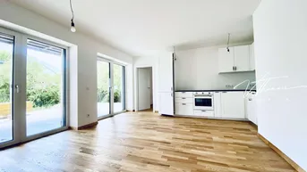 Helles, offenes Wohnzimmer mit integrierter Küche, Holzboden und Zugang zur Terrasse.