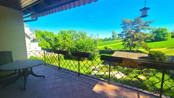 Geräumiger Balkon mit Sitzgelegenheiten und weitem Blick ins Grüne unter einem Sonnendach.