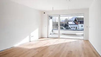 Virtuell inszenierter heller Raum mit Holzboden und großem Schiebefenster zum Balkon mit Bergblick.