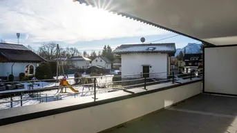 Sonniger Balkon mit Fliesenboden und Blick auf die verschneite Nachbarschaft und Berge.
