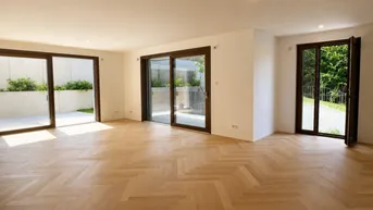 Heller Wohnbereich mit Fischgrätparkett und Zugang zu Terrasse und Balkon, umgeben von Grün.