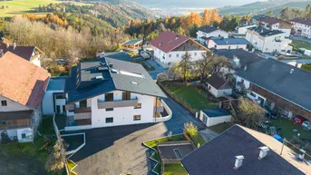 Weitläufige Luftaufnahme des Gebäudes in ländlicher Umgebung mit Herbstbäumen und Bergen.