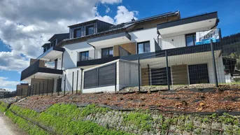 Modernes Mehrfamilienhaus mit Balkonen und zeitgenössischer Architektur in alpiner Umgebung.