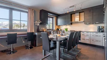 Moderne Küche mit Essbereich, Bergblick und dunklen Holzschränken, ideal für gesellige Mahlzeiten.