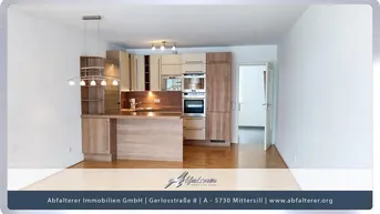 Moderne offene Küche mit Holzelementen und integrierten Geräten, die in einen hellen Wohnbereich übergeht.