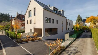 Neubaugebäude mit moderner Architektur, Satteldach und Zufahrt zu den Parkplätzen.