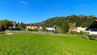 Großes grünes Grundstück mit Blick auf die umliegende Landschaft und Häuser in der Ferne.