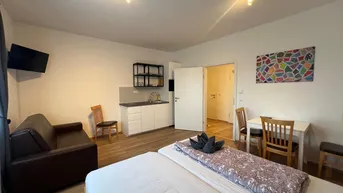 Gemütlicher Wohnbereich mit Bett, Sofa, Esstisch und integrierter Küchenzeile.
