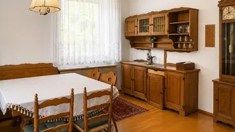 Traditioneller Essbereich mit rustikalen Holzmöbeln, großem Fenster und einer Standuhr.