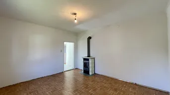 Geräumiges Wohnzimmer mit Parkettboden und einem gemütlichen Kaminofen.