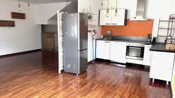 Offener Wohn- und Essbereich mit integrierter Küche, Holzboden und modernen Hängelampen.