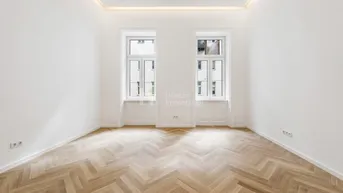 Helles Zimmer mit elegantem Fischgrätparkettboden und zwei großen Fenstern.