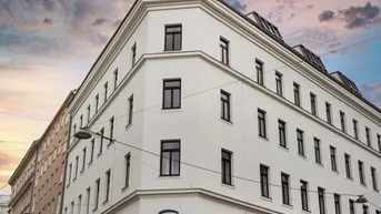 Eckgebäude mit klassischer Architektur und vielen Fenstern unter einem dramatischen Himmel.