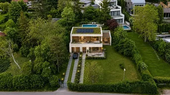 Moderne Villa mit Gründach, Photovoltaikanlage, Pool und weitläufigem Garten in grüner Umgebung.