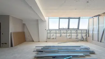 Geräumiger Innenraum im Rohbau mit großen Fenstern und Blick nach draußen.
