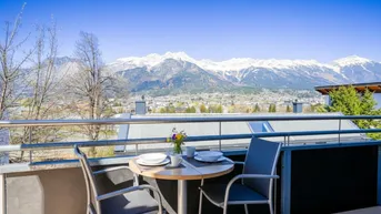 Balkon mit Esstisch und Stühlen bietet einen weiten Blick auf die schneebedeckten Berge.