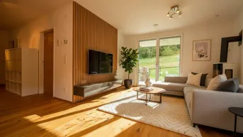 Helles Wohnzimmer mit Holzboden, gemütlichem Sofa und Zugang zur Terrasse mit Blick ins Grüne.