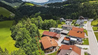 Luftaufnahme des Anwesens in einer grünen Umgebung mit Bergen im Hintergrund.