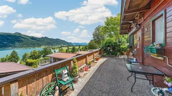 Große Terrasse mit Seeblick und Bergblick, umgeben von grüner Natur und Holzelementen.
