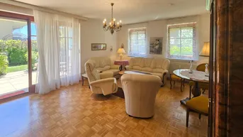 Gemütliches Wohnzimmer mit Parkettboden, beigen Sofas und Zugang zur Terrasse und zum Garten.