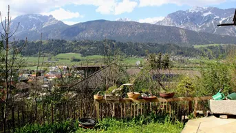 Grüner Gartenbereich mit Holzzaun und weitem Blick auf die umliegende Berglandschaft.