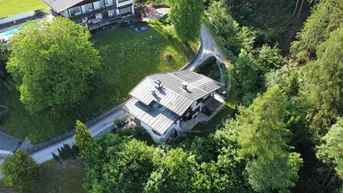 Panoramablick auf ein charmantes Wohnhaus in ländlicher Umgebung mit viel Grün und einer Zufahrtsstraße.