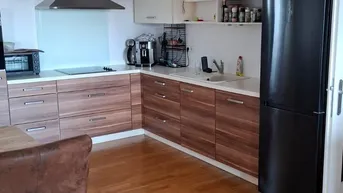 Moderne Küche mit Holzfronten, integrierten Geräten und dunklem Kühlschrank.
