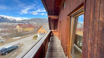Geräumiger Holzbalkon mit traditionellem Design und weitem Blick auf die umliegende Berglandschaft.