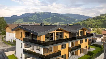 Modernes Apartmentgebäude mit Holzfassade, Balkonen und Bergblick in einer grünen Umgebung.